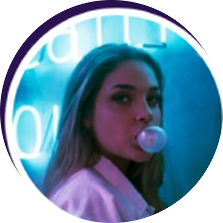 Tina, blowing a bubble of gum in front of a teal neon sign